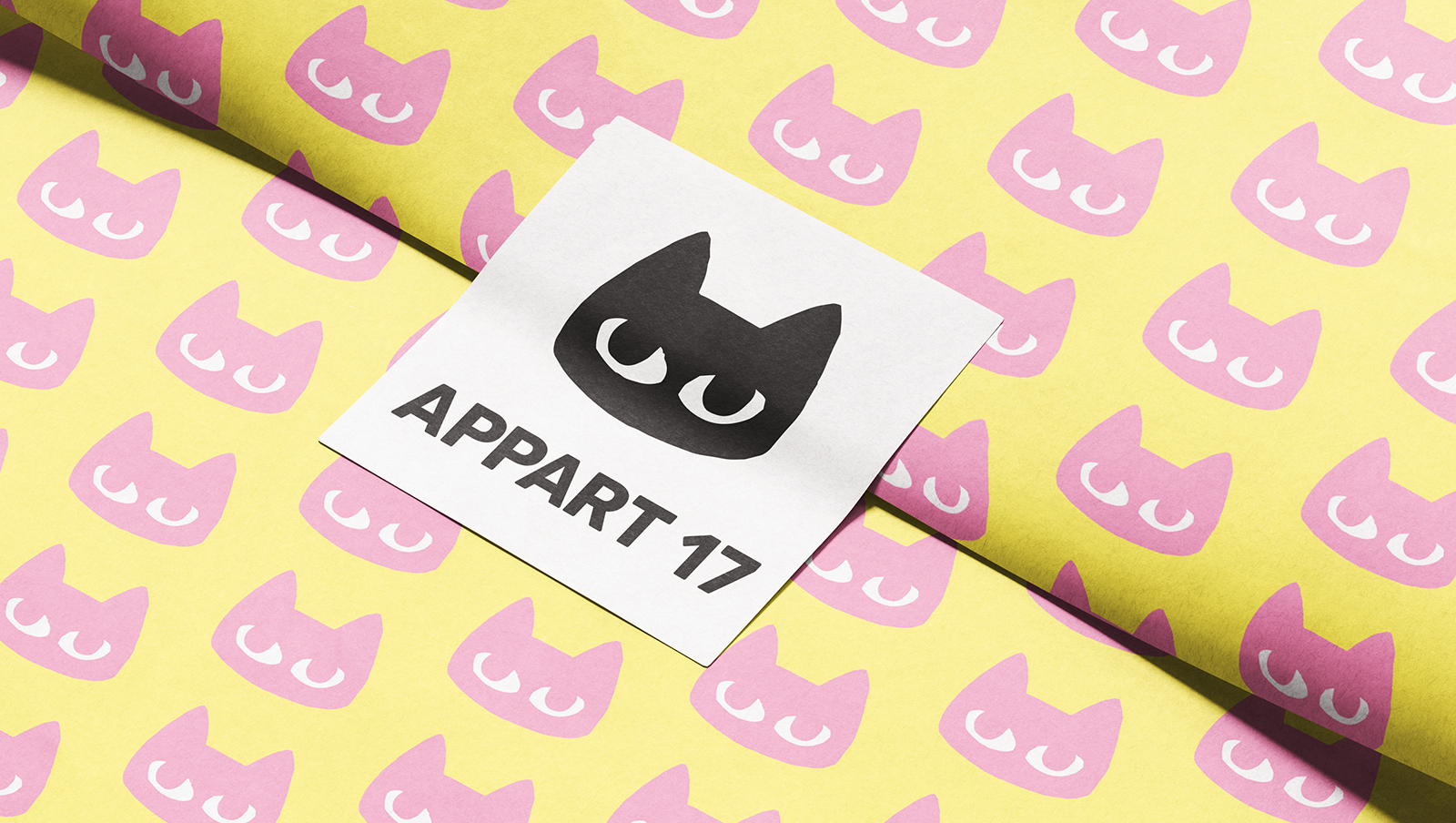 Étiquette jaune avec logo chat Appart 17 sur fond textile rose